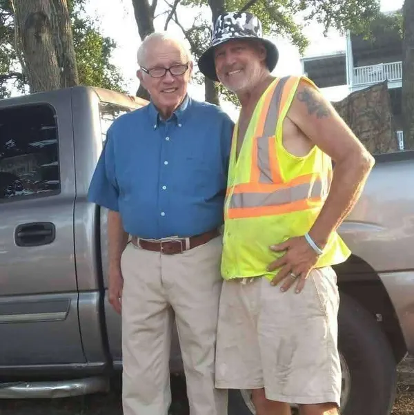Dagwood in a blue shirt and khakis standing with Andy at the lot