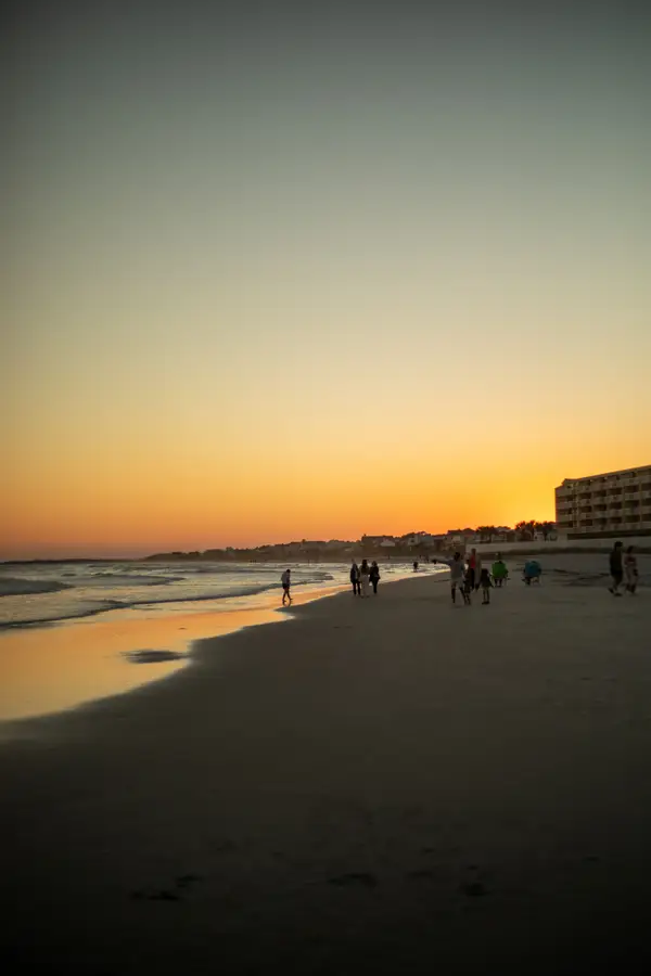 Folly Beach at sunset with people walking along the water